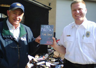 Fire Sale, Rescued After a fire in the Durham County, NC Library shed, Supervisor Ronald Butler and Fire Marshall Michael Webb hold a rescued copy of Fire Sale.